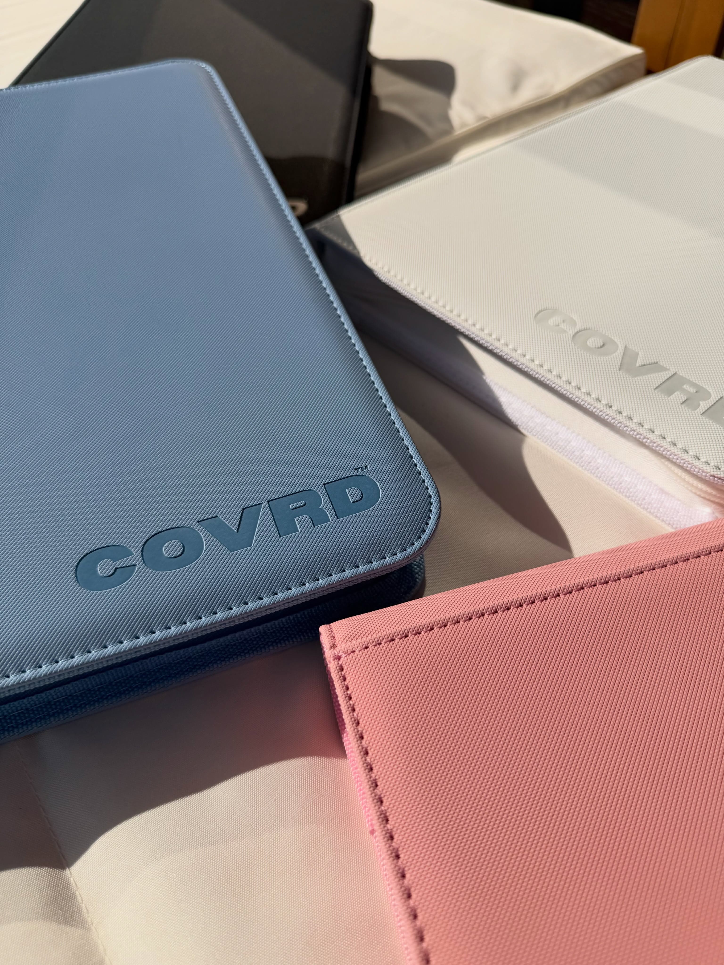 COVRD zip binders in steel blue, white, black, and blush pink